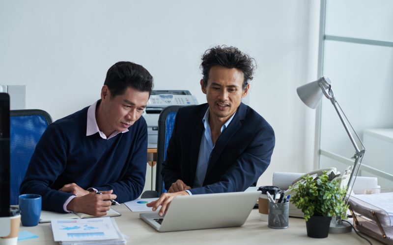 Businessman showing presentation on laptop screen to his colleague