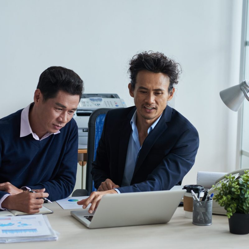 Businessman showing presentation on laptop screen to his colleague